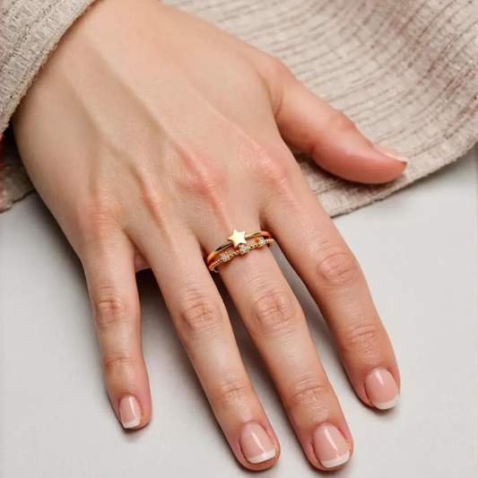 A gold-plated adjustable gold ring with a star charm and cubic zirconia stones on a person's finger.